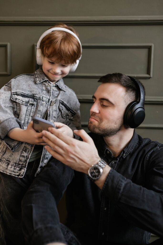 Baba ve oğlu evde birlikte kulaklıkla müzik dinliyor.