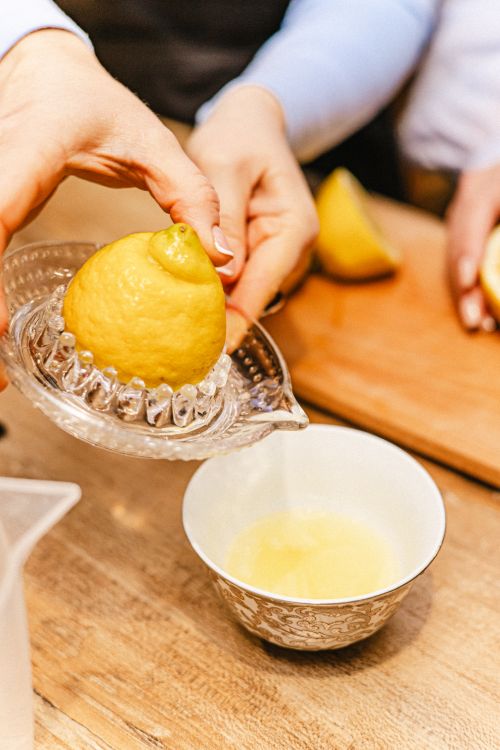 Bir yetişkin mutfakta limonu cam sıkacakla sıkarak suyunu hazırlıyor.